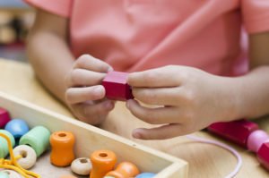 Montessori Spielzeug in Hand eines Kindes